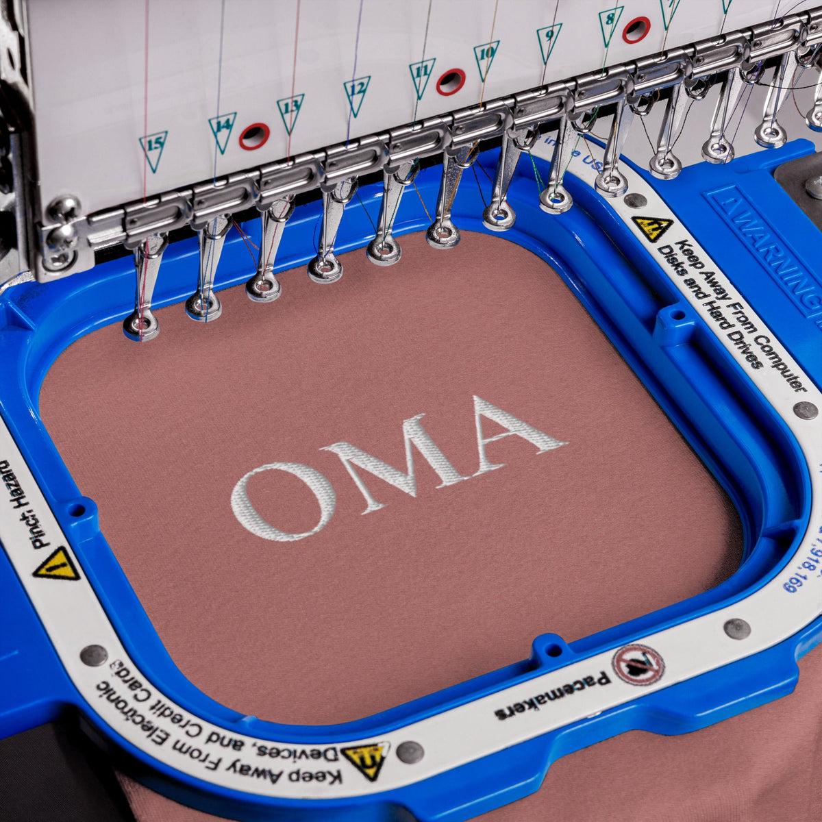 Die OMA Stickerei entsteht in der Stickmaschine, altrosa Stoff im Rahmen
